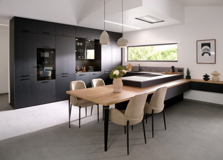 Black kitchen with oak dining table and beige chairs