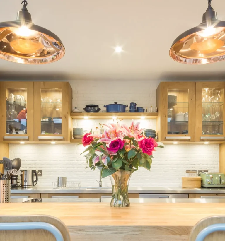 Oak glass-fronted cabinets with copper pendants and flowers