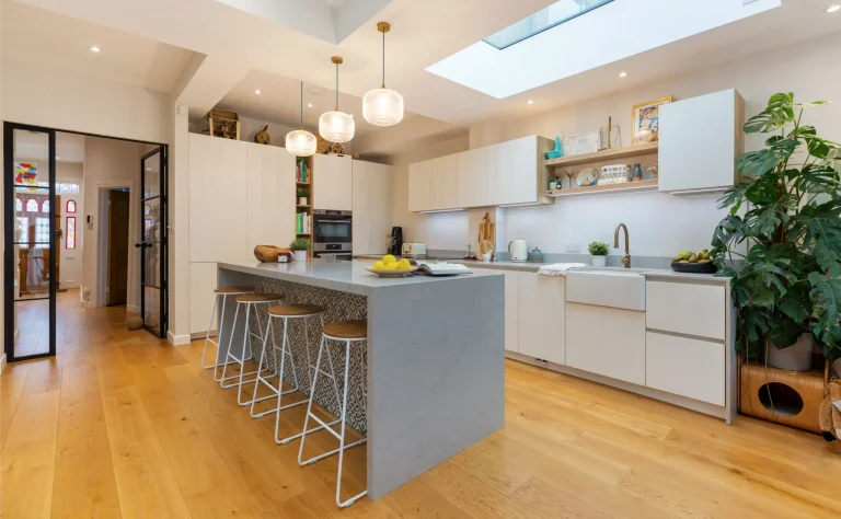 Light grey kitchen island with bar stools and pendant lights