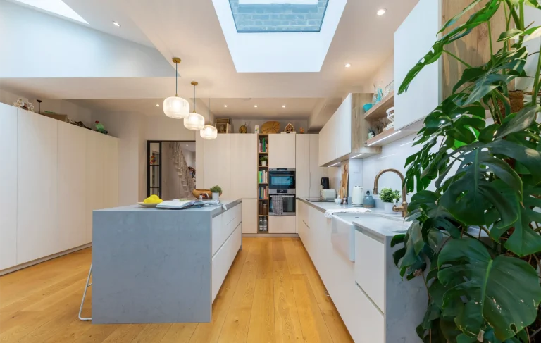 Light grey island in a white kitchen with skylight
